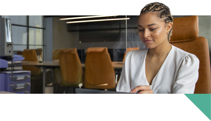 Uma mulher negra com cabelo trançado olhando para um notebook.